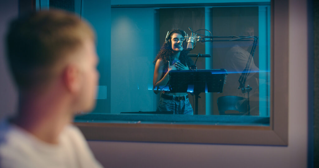 recording studio, musician and woman with producer for singing songs, track and audio for album. creative, musical industry and artist in booth with technician for performance, sound and rehearsal