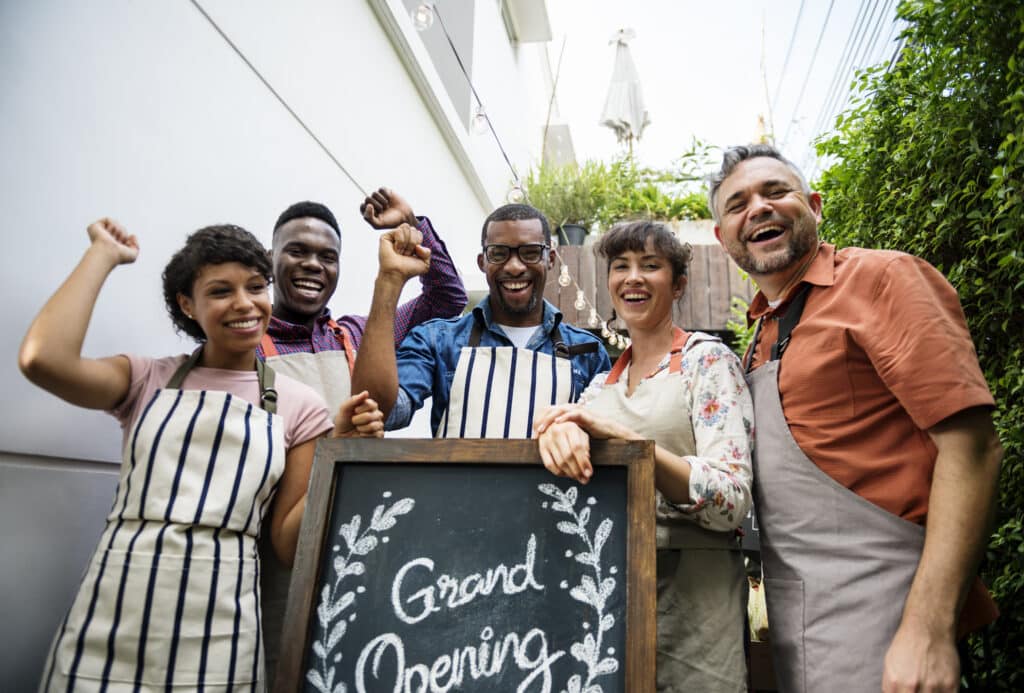 diverse people with grand opening sign first day of business